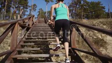 女孩跑步者从码头爬上木制楼梯。 跑步运动员在楼梯上跑步。